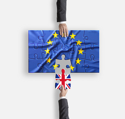 Brexit businessmen hands removing flag of UK from Europe on jigsaw puzzle