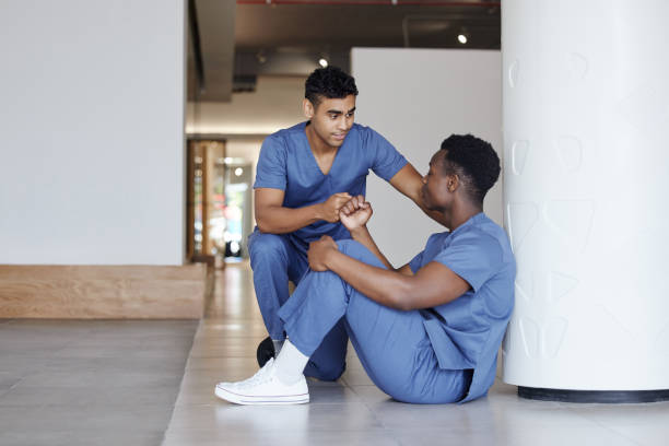 photo d’un jeune médecin masculin consolant un collègue au travail - medical check photos et images de collection