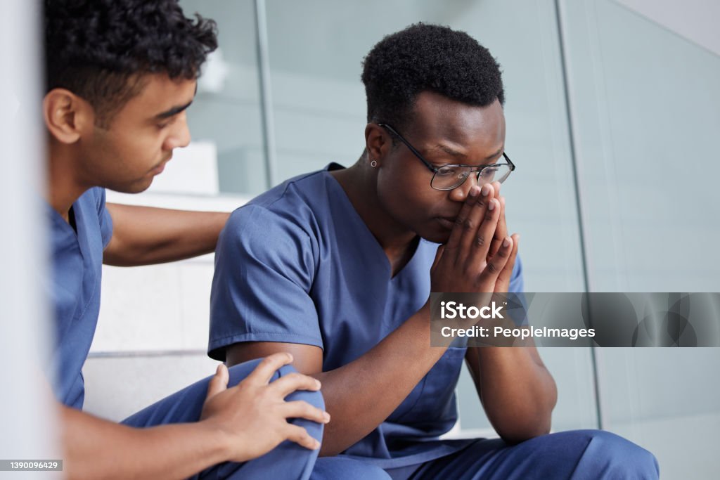 Shot of a young male doctor consoling a coworker at work Are you okay? Consoling Stock Photo