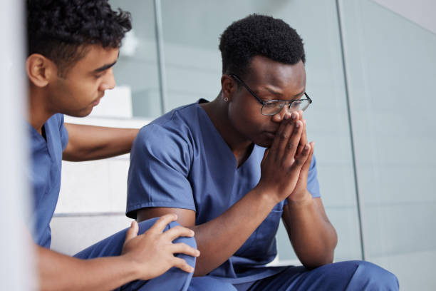 shot of a young male doctor consoling a coworker at work - female emotional stress african ethnicity loss imagens e fotografias de stock