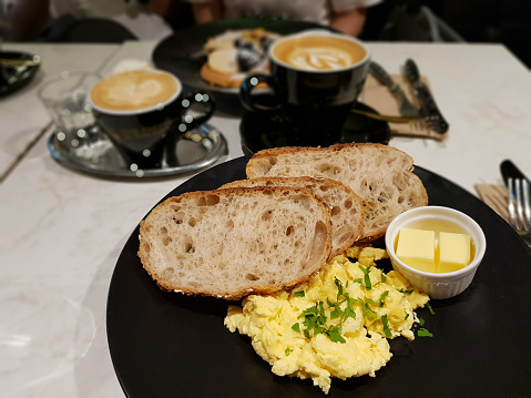 Healthy brunch with ciabatta, scrambled egg and butter. WIth a cup of latte
