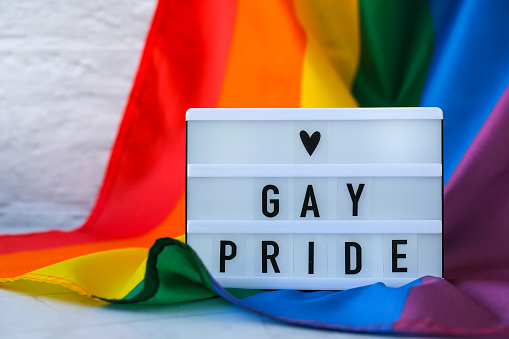 Rainbow flag with lightbox and text GAY PRIDE. Rainbow lgbtq flag made from silk material. Symbol of LGBTQ pride month. Equal rights. Peace and freedom. Support LGBTQ community