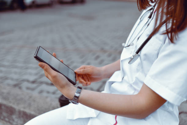 istock Nurse Sitting Outside, Drinking Coffee And Using Banking App To Make Investment 1390099265