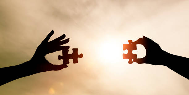 istock Two hands put two pieces of the puzzle together 1390100611