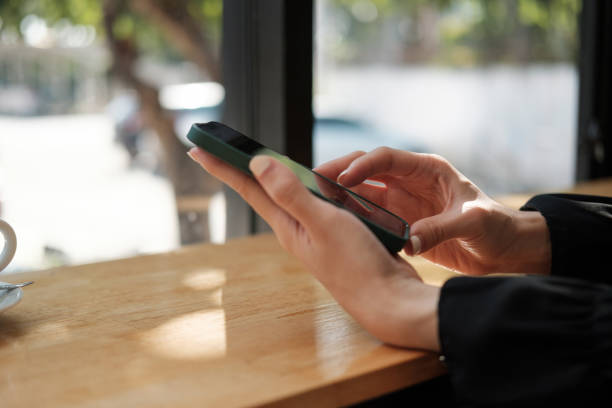 istock Close up hand of woman using mobile phone at cafe coffee shop 1390101310