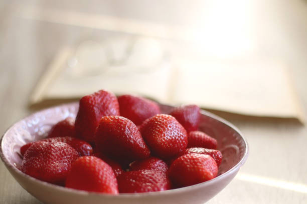 istock Bowl of Strawberries, Open Book and Reading Glasses 1390101837