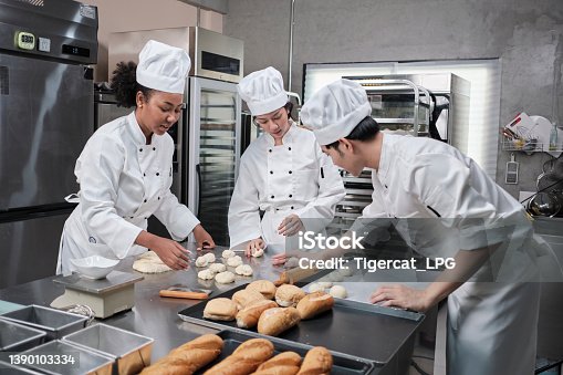 istock Chefs team in uniforms prepare to bake bread and pastry in stainless kitchen. 1390103334