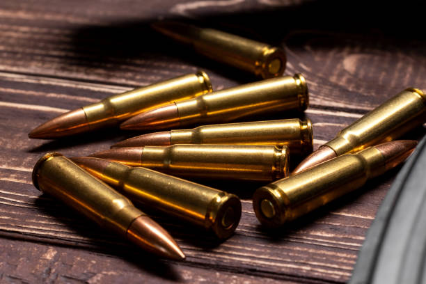 istock Bullets for Kalashnikov assault rifle on wooden background 1390103416