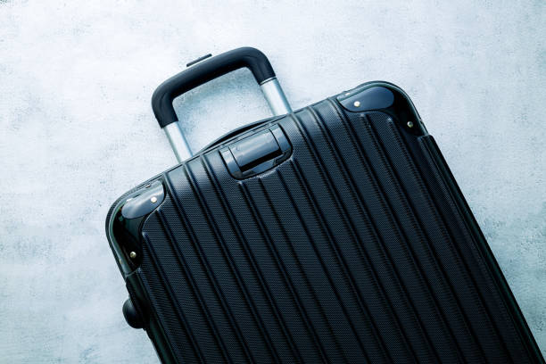 istock black travel bag,Black luggage set on dark background, top view image, flat lay composition. Travel minimalist concept, black and dark classic baggage mockup, small and big. Suitcase accessory set, journey concept. 1390104739
