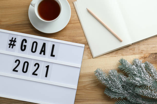 istock Light box with hashtag Goal 2021 near notebook, new year targets. Flat lay composition on wooden table 1390107055