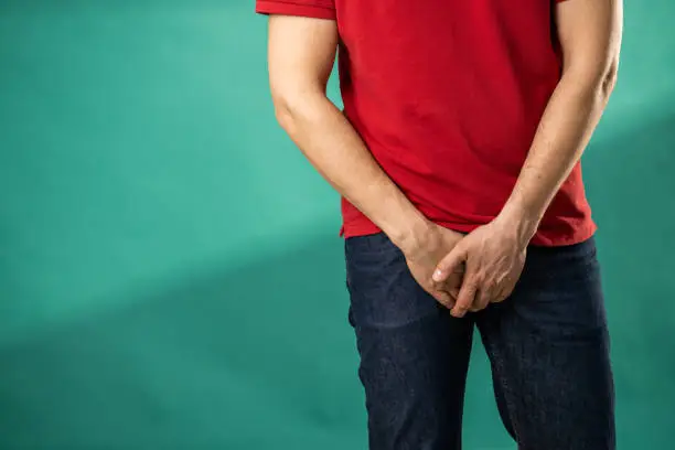 Man with urinary system problems holding hands on his crotch.