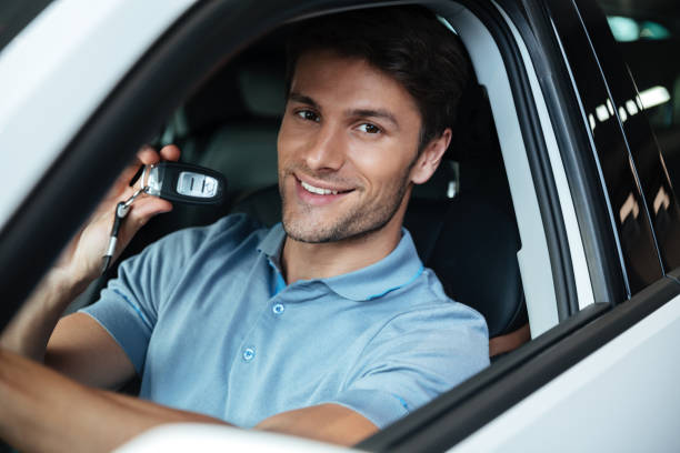 Handsome happy man sitting in his new car