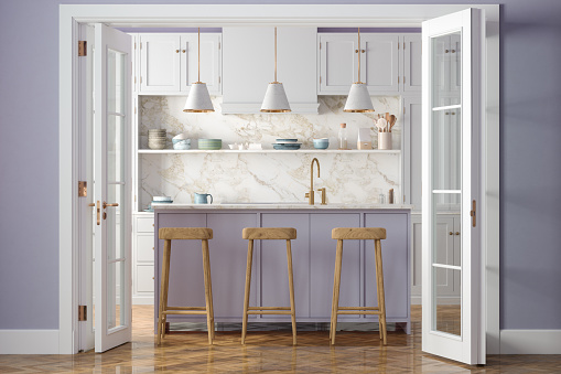 Entrance Of Modern Kitchen With White Cabinets, Kitchen Island, Pendant Lights, Wooden Stools And Purple Wall In Background