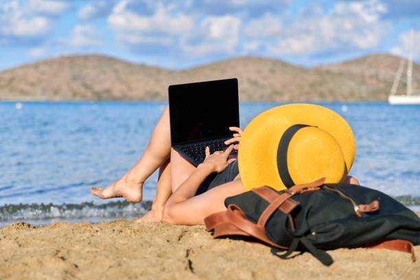 istock Mature woman sunbathing on the beach using a laptop 1390117140