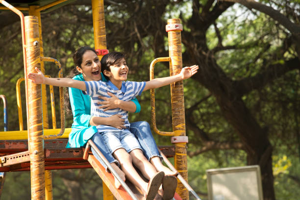istock Mother with son having fun on slide at playground 1390117183