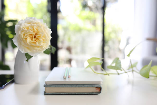 istock Notebooks and pencils and vase of rose 1390120236