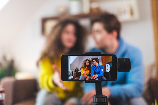 Smart phone sitting on a gimbal. A couple is recording themselves vlogging on a smart phone. Content creators. YouTubers.