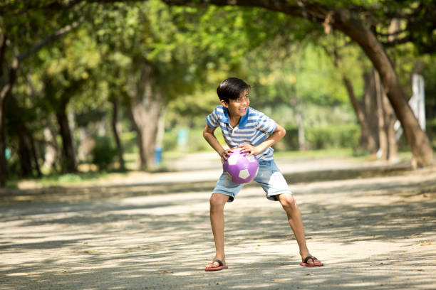 Smiling little boy, 5 years old, holding a yellow soccer ball. A child in sunglasses, a summer day, enjoys the holidays, plays in kindergarten