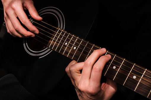 man learning to play the guitar close-up
