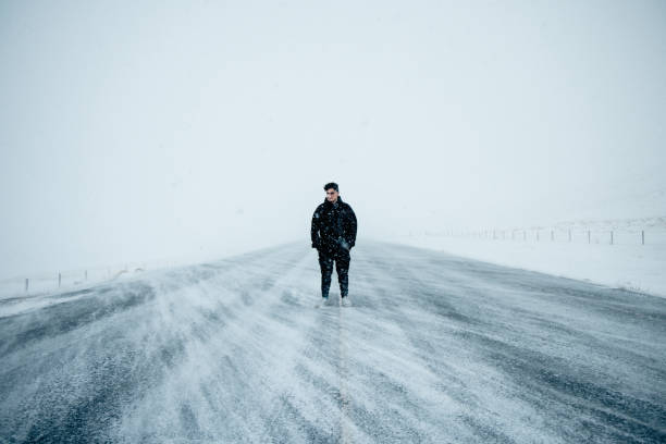Young Man on Middle of Snow Covered Country Road Iceland Highlands stock photo