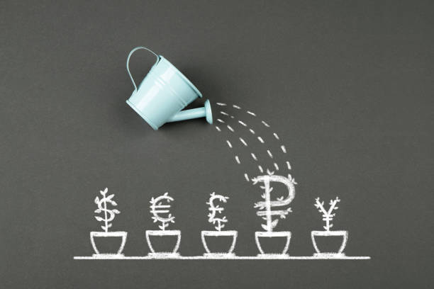 istock Watering can and currency signs growing in pot 1390124272