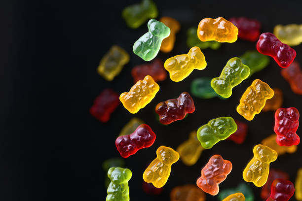 istock Multicolored flying gummy bears on a black background, flat lay 1390124284