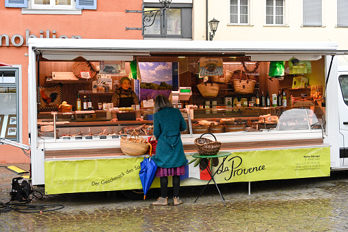 Ueberlingen, Germany, March 30, 2022 - Unidentified people on the Ueberlingen weekly market in the heart of the old town on a rainy day