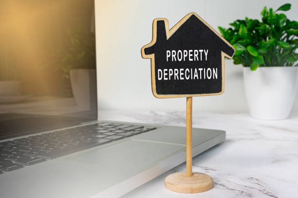 istock Property depreciation text on wooden house model with notebook on white desk. 1390127132