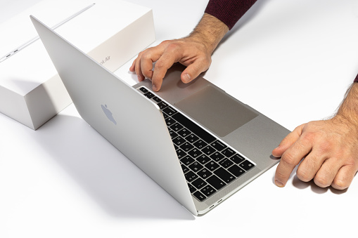 Saratov, Russia - February 26, 2022: turn on Macbook Air 13 inch with M1 processor. Unpacking new Apple laptop closeup, white background. Advertising of modern technology and portable device.