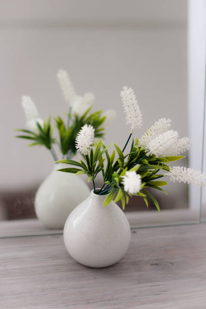 istock White vase on white in front of a mirror with flowers. 1390128339