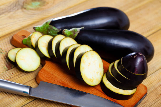 istock Whole and sliced fresh eggplant on wooden table 1390128850