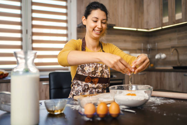 istock Young woman combining ingredients and making dough in the kitchen 1390130506