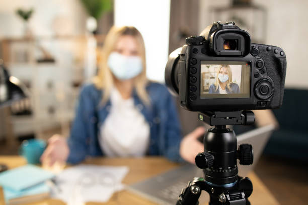 istock Woman in protective mask using camera for recording video 1390131179