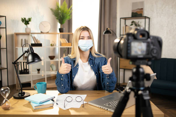 istock Happy woman in mask talking showing thumb up on camera 1390131184