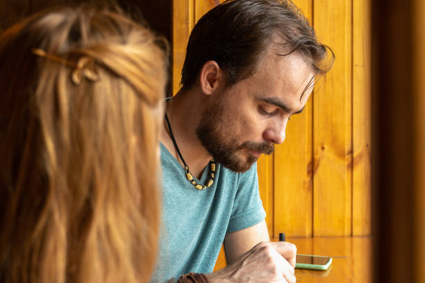 istock Young man having dinner in little cafe while sitting at the table near window 1390131263
