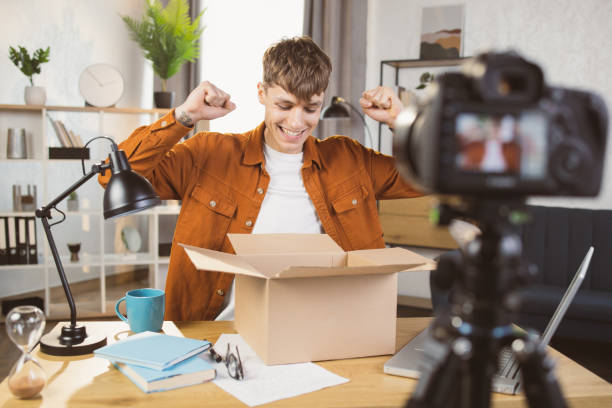 istock Man filming on camera unpacking process of paper box 1390131503
