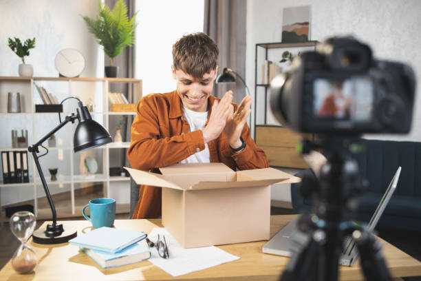 istock Man filming on camera unpacking process of paper box 1390131507