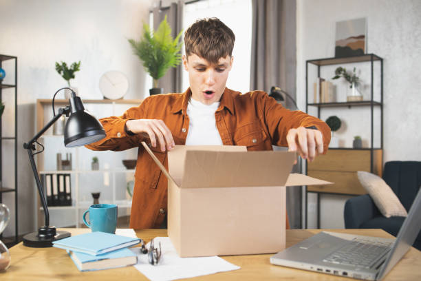istock Excited young Caucasian man opening box with ordered goods at home 1390131518