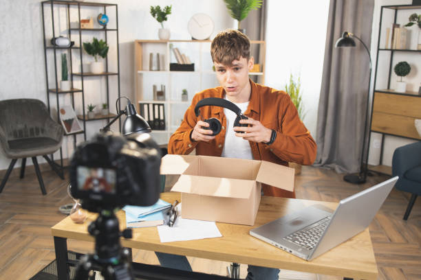 istock Man recording video while unpacking box with headphones 1390131525
