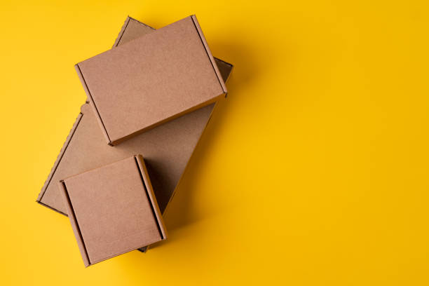istock Beige cardboard boxes on yellow background, close up 1390133760