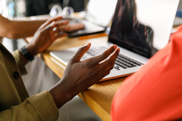 Close up shot of unrecognizable businessman sitting at conference table, gesturing while sharing his ideas with colleagues during a meeting.