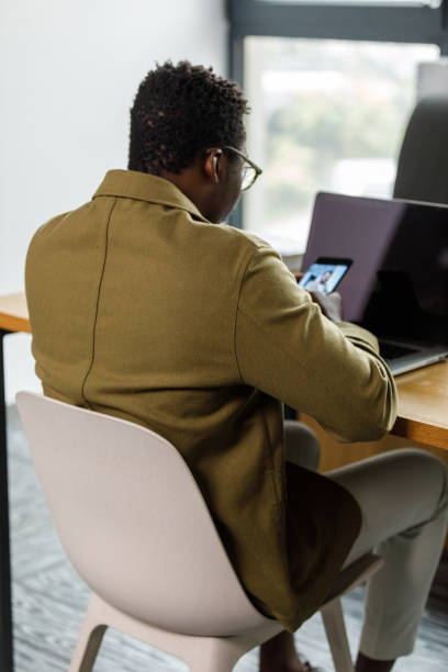 istock Young businessman sitting at his desk, using smart phone to pass time 1390134145