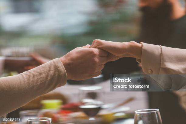 Unrecognizable people holding hands and praying before having lunch