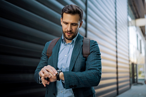 Young casual businessman checking the time