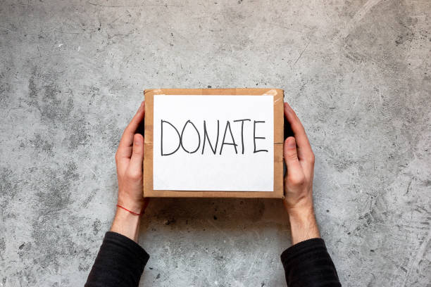 con in mano una scatola con donazioni in mano, aiuti umanitari su sfondo grigio - jar currency donation box charity and relief work foto e immagini stock
