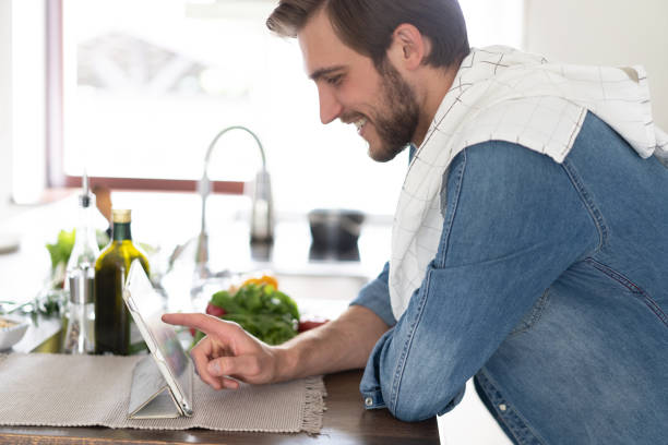 istock cooking, technology and home concept - man reading recipe from tablet pc computer. 1390139037