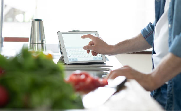 istock cooking, technology and home concept - man reading recipe from tablet pc computer. 1390139038
