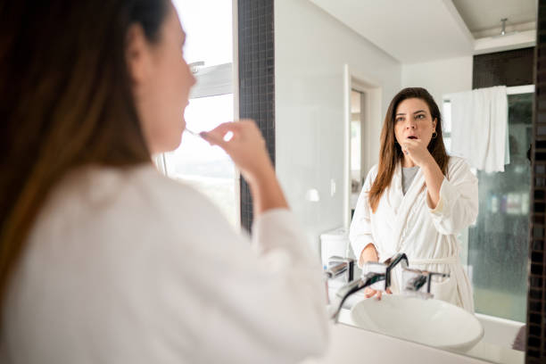 istock Woman brushing her teeth in her bathroom mirror 1390140186