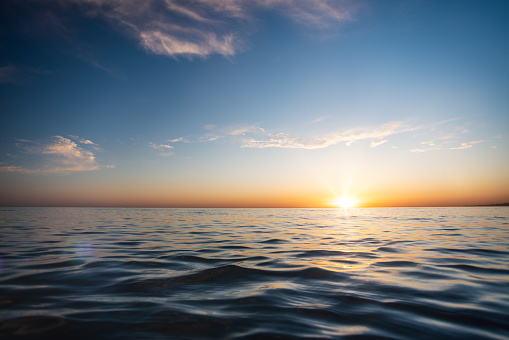 Stunning sunset over the sea. View from a low angle right at the water’s surface and bright sun corona on the horizon