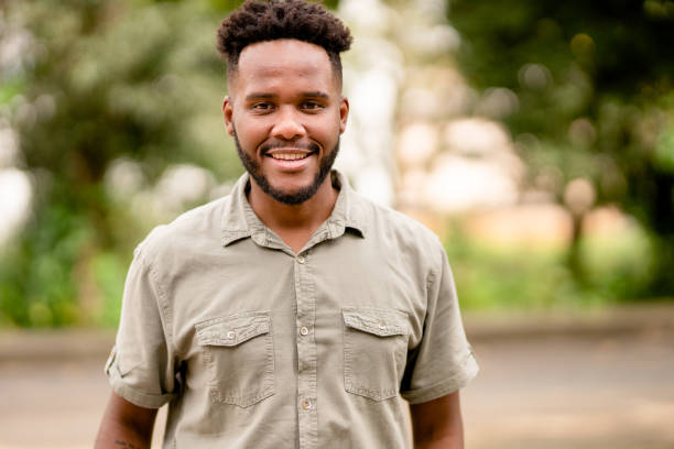 istock Young man smiling while standing outside in summer 1390142969